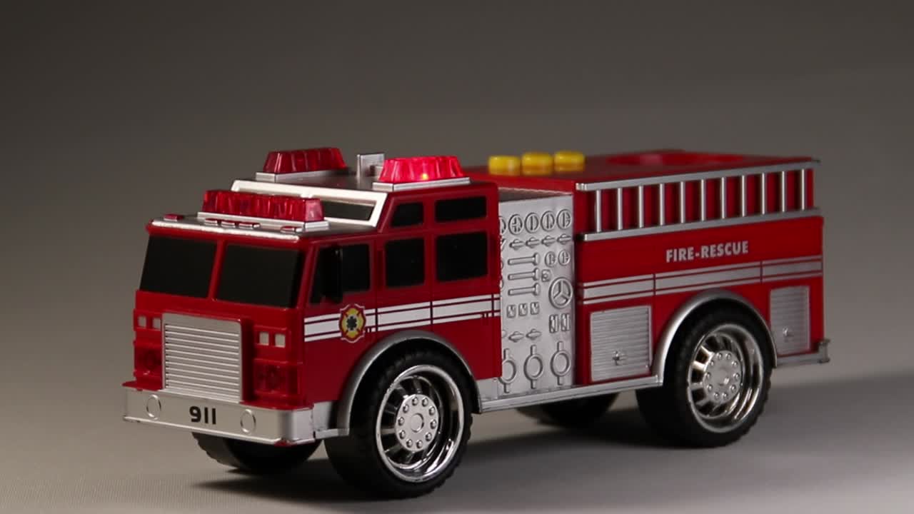 Dymanic zoom footage of toy fire truck with red flashing lights.