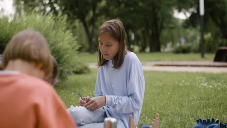 Rear-view-of-a-boy-sitting-in-the-park.-On-the-backgroudn-a-blonde-girl-is-making-crafts