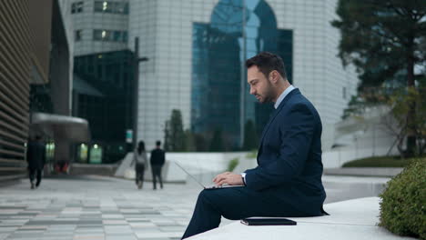 businessman working sitting on the bench outside an office building