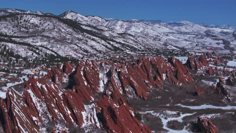 Stunning-March-winter-morning-snow-Roxborough-State-Park-Littleton-Colorado-aerial-drone-sharp-jagged-dramatic-red-rock-formations-Denver-foothills-front-range-landscape-blue-sky-backwards-motion