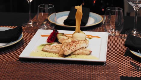 plato de salmón con salsa de mostaza en la mesa con vasos de vino de cristal en un restaurante de lujo