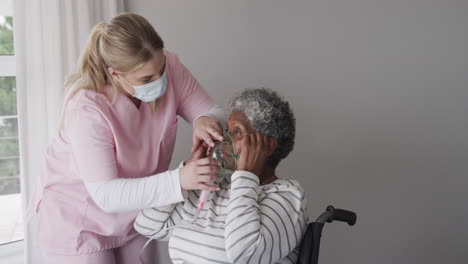 caucasian female nurse in face mask, senior african american woman with oxygen mask, slow motion