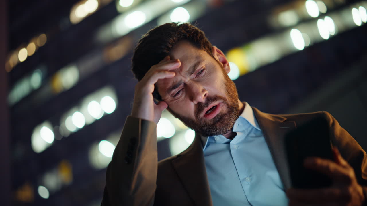 Late executive checking smartphone outside night buildings portrait. Upset ceo