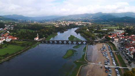 Stunning-aerial-4K-drone-footage-of-a-village---Ponte-de-Lima-in-Portugal-and-its-iconic-landmark---Stone-roman-bridge-crossing-over-the-Lima-River