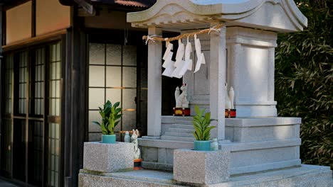 Pequeño-Santuario-De-Piedra-De-Ofrenda-Con-Estatuas-De-Zorros-En-Un-Santuario-Típico-Japonés