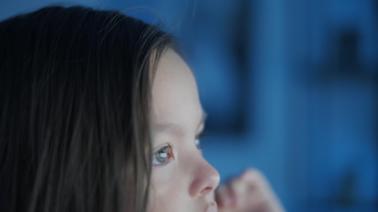 어린 소녀가 컴퓨터 앞에 앉아서 강한 감정을 표시합니다. 이 장면은 편안한 실내 환경에서 펼쳐지는 매력적인 순간 동안 그녀의 표현적 반응을 포착합니다.