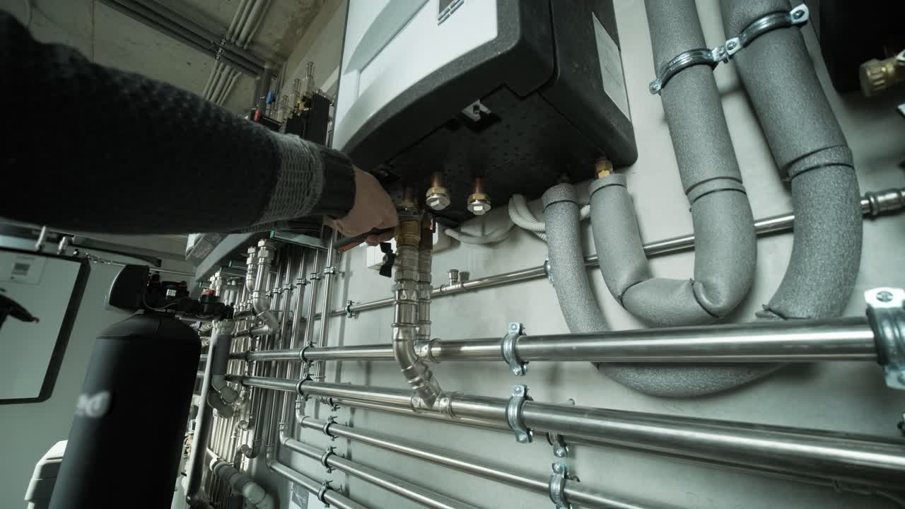 Technician adjusting modern heating system with pipes and control units