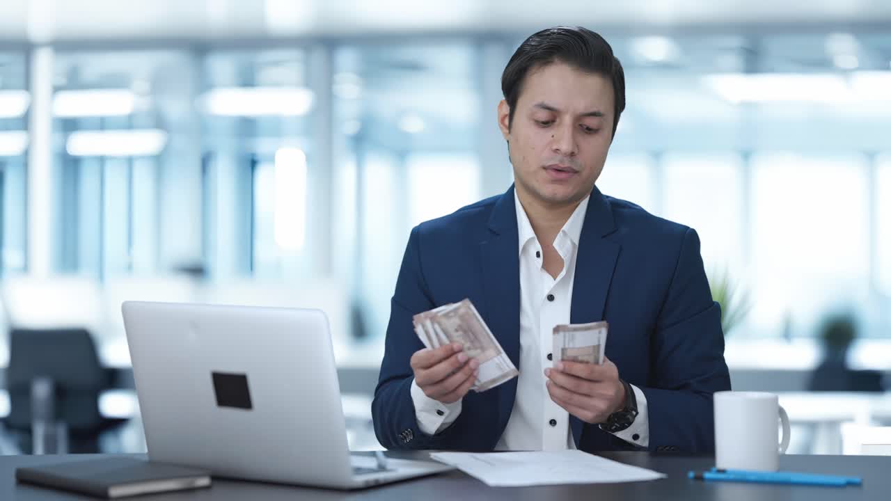 オフィスでお金を数えるインド人ビジネスマン
