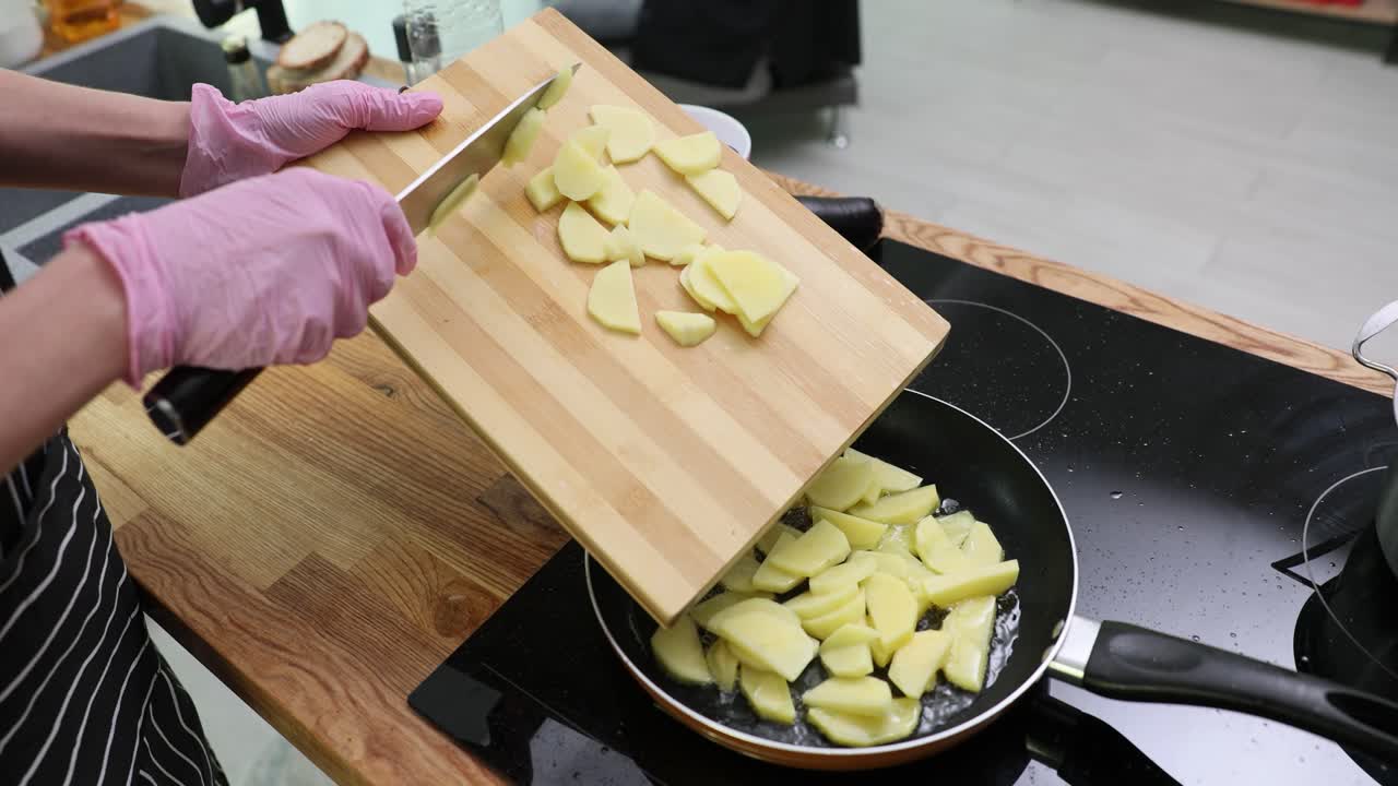 Preparing Potatoes: Transferring Sliced Potatoes from Cutting Board to Frying Pan