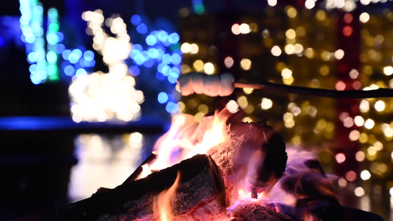 Close up of marshmallows warming up on a burning fireplace with Christmas decor on the background