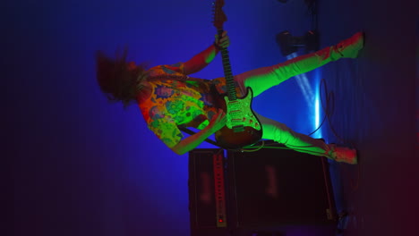 vertical video of a dancing gay man playing guitar on a changing background light and strobe lights of a concert light. bright neon lights