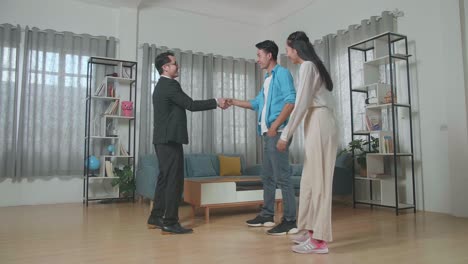 full view of asian real estate agent shaking hands with a man walking side by side a woman before talking about the house for sale