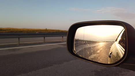 reflection side rear view car mirror in the morning on the road at sunset or sunrise