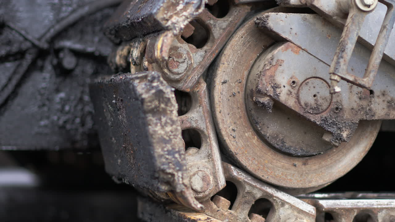 도로 건설 현장에서 천천히 움직이는 트랙 페이버의 세부 뷰 - 클로즈업