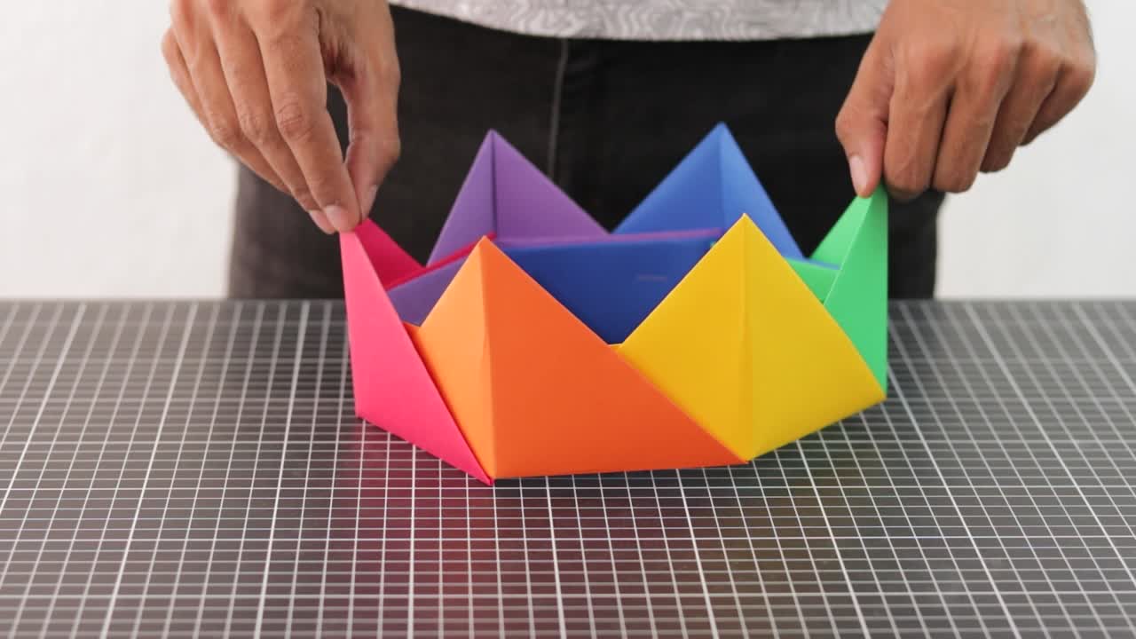 다채로운 손으로 만든 무지개 종이 왕관을 보여주는 손