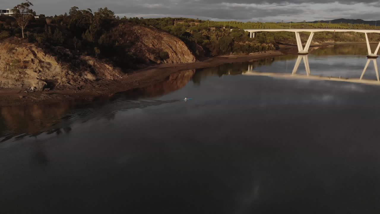 Canoista solitario sul tranquillo fiume Mira, diretto verso il ponte.