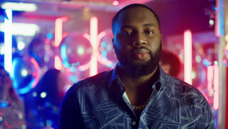 serious african man staring at lens in club. afro guy spending time at party