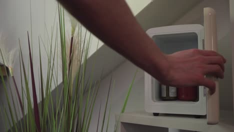 refrigerador pequeño en la oficina de casa, sacando un frasco pequeño