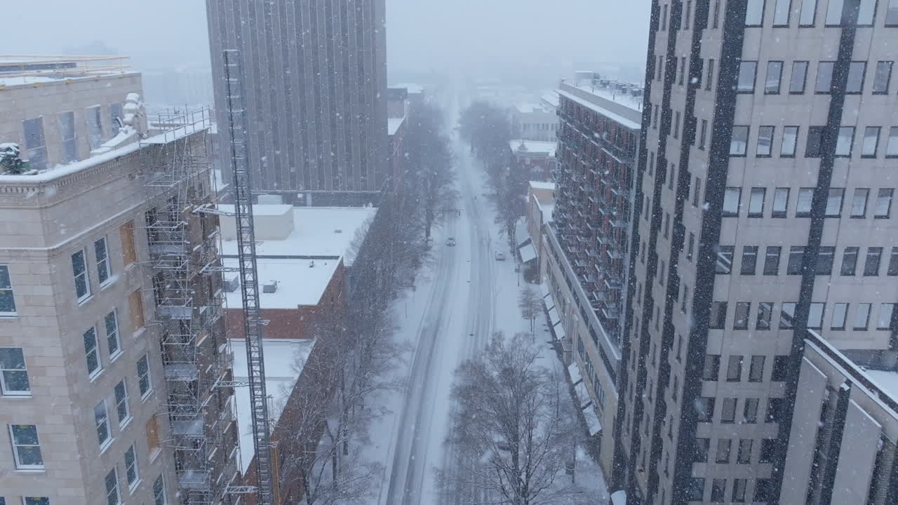 Aerial footage during a snowstorm in Chattanooga, TN panning up in downtown to reveal tall buildings.