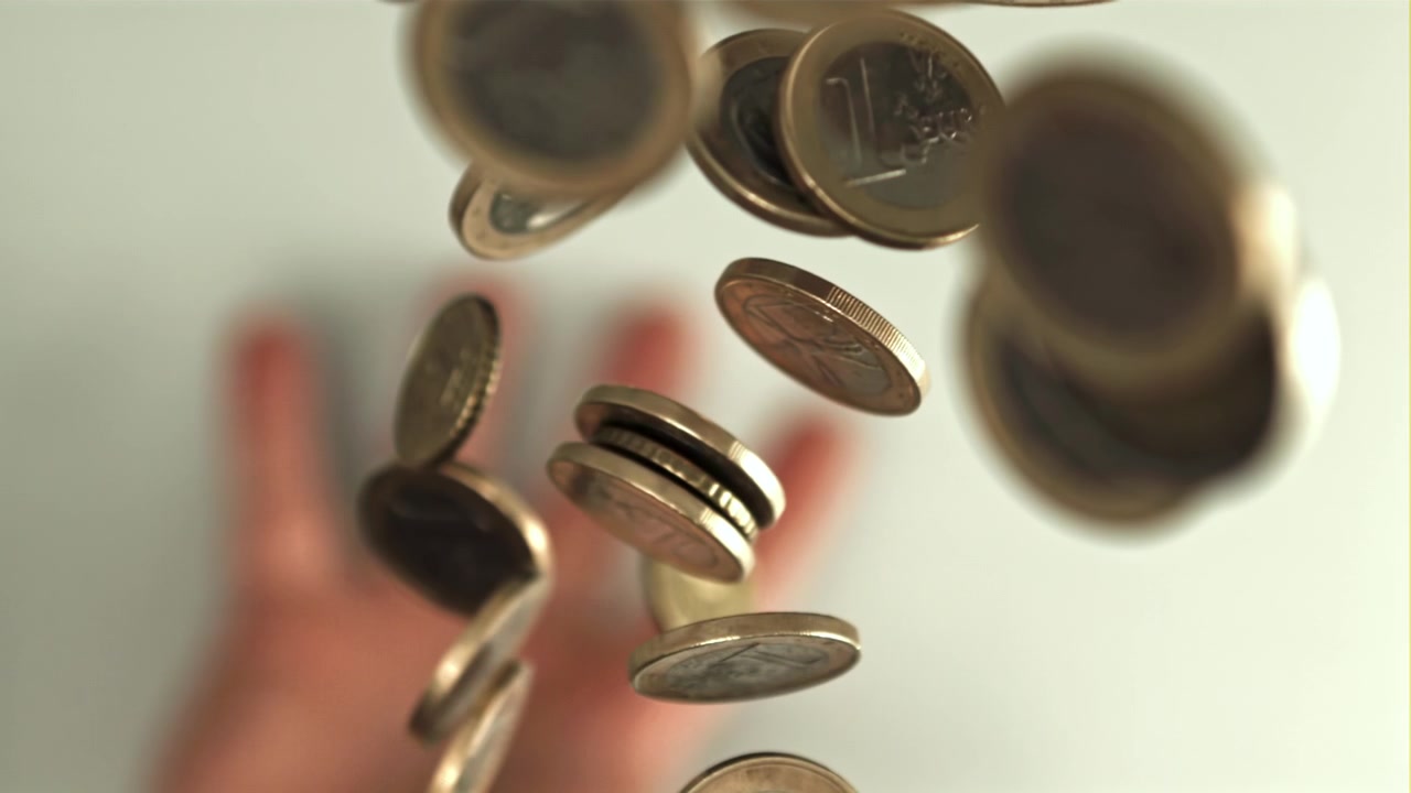 Euro Coins Falling in Slow Motion with a Blurred Hand in the Background