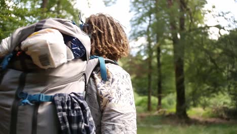 guy with dreadlocks and a backpack in a blouse walking trough the woods in luxembourg