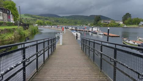 POV-walking-down-ramp-to-floating-marina-dock-on-river-in-lush-Ireland