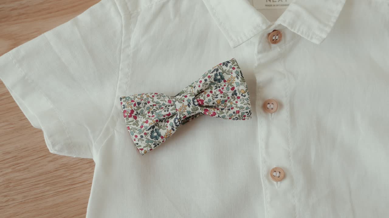 Primer plano de pajarita con estampado floral sobre elegante camisa blanca
