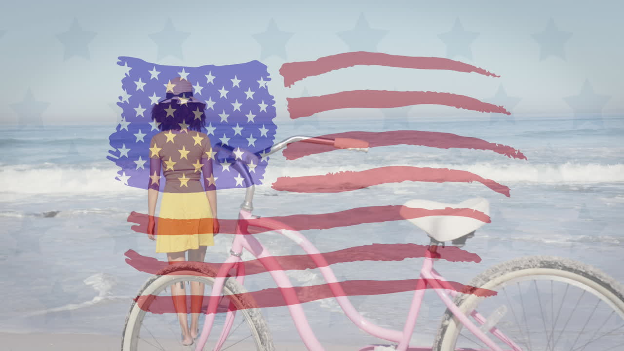 bandeira americana acenando contra a vista traseira da mulher afro-americana com bicicleta de pé na praia