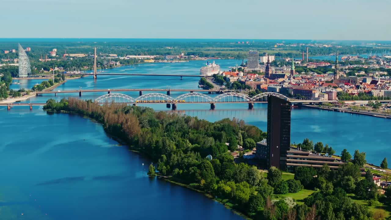 Wide aerial descent over green islands and urban skyline in Riga Latvia summer