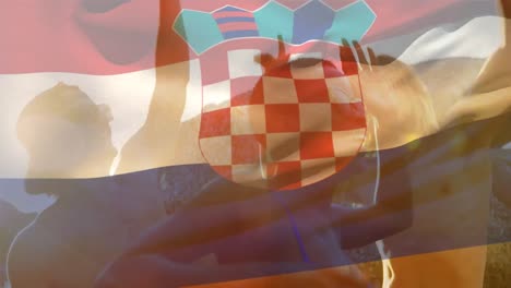 Animation-of-waving-croatia-flag-over-group-of-friend-on-the-beach