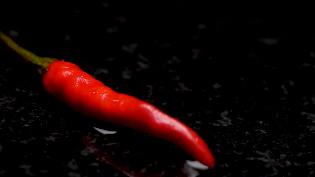 검정색 배경 타일에 있는 촉촉한 붉은 고추, 슬라이딩 샷