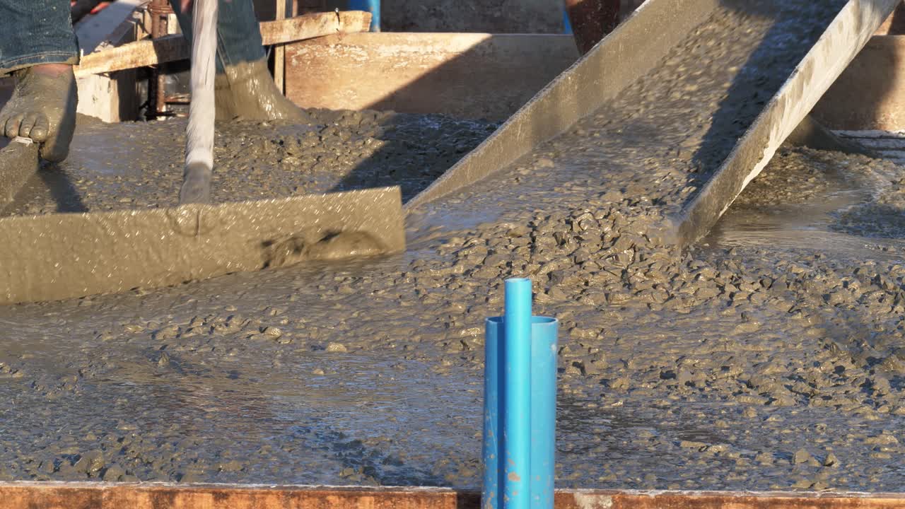 varios trabajadores de la construcción están realizando actividades de fundición para nivelar la mezcla de hormigón para el piso