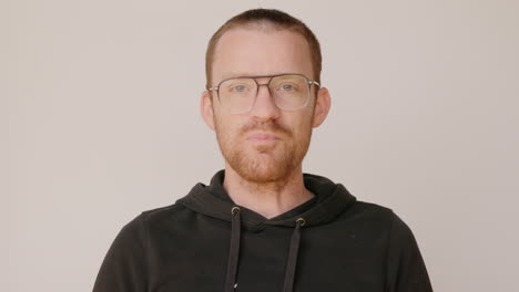 red haired man in a dirty hoodie drinking water from a wine glass on a white backdrop