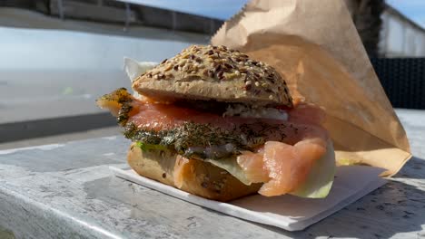 beach sandwich with smoked salmon on wood table by the beach