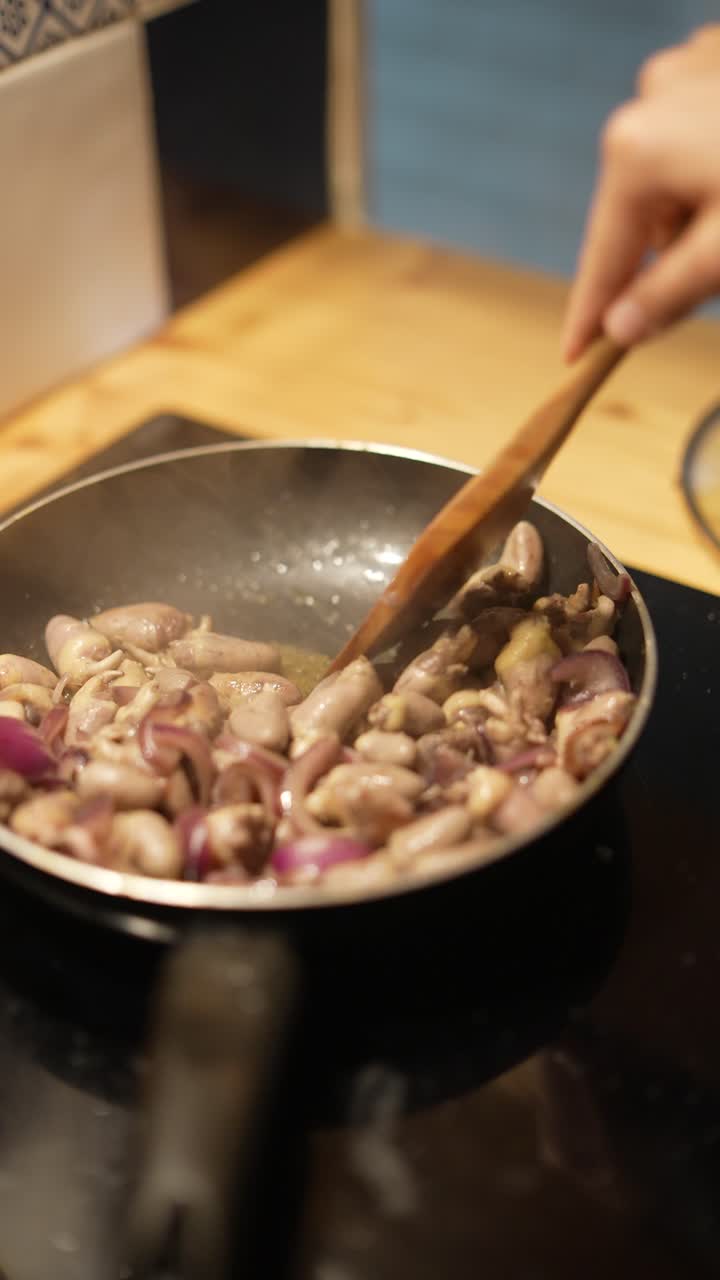 cocinar corazones de pollo con cebollas en una sartén