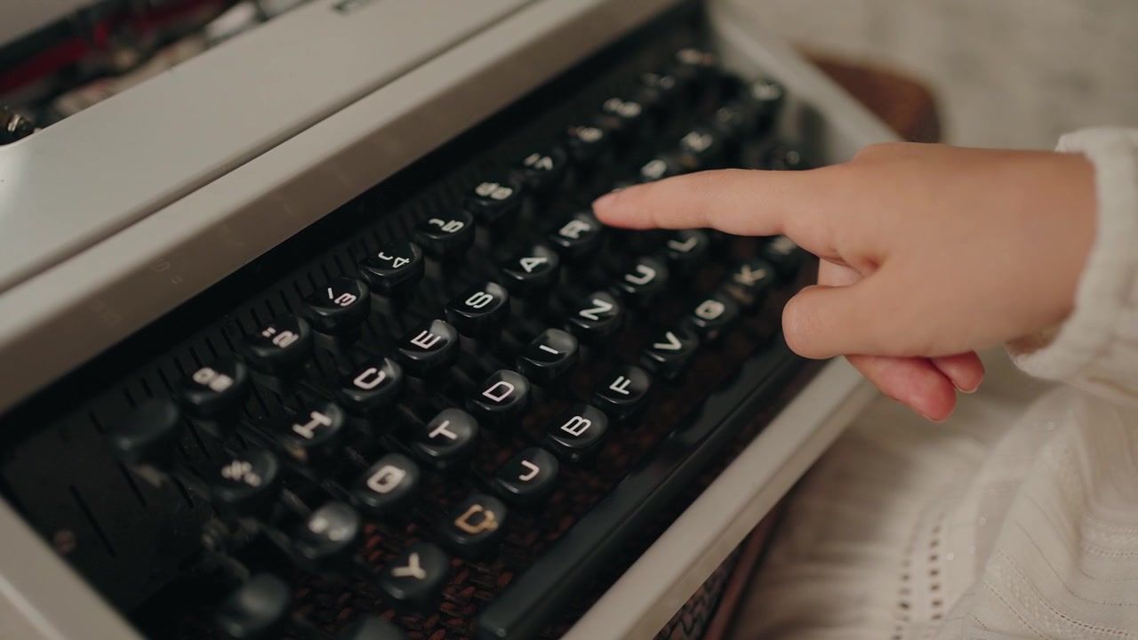 Primo piano di un dito che preme un tasto su una macchina da scrivere vintage in dettaglio