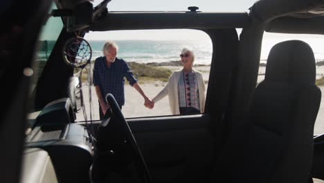 senior couple with a car at the beach