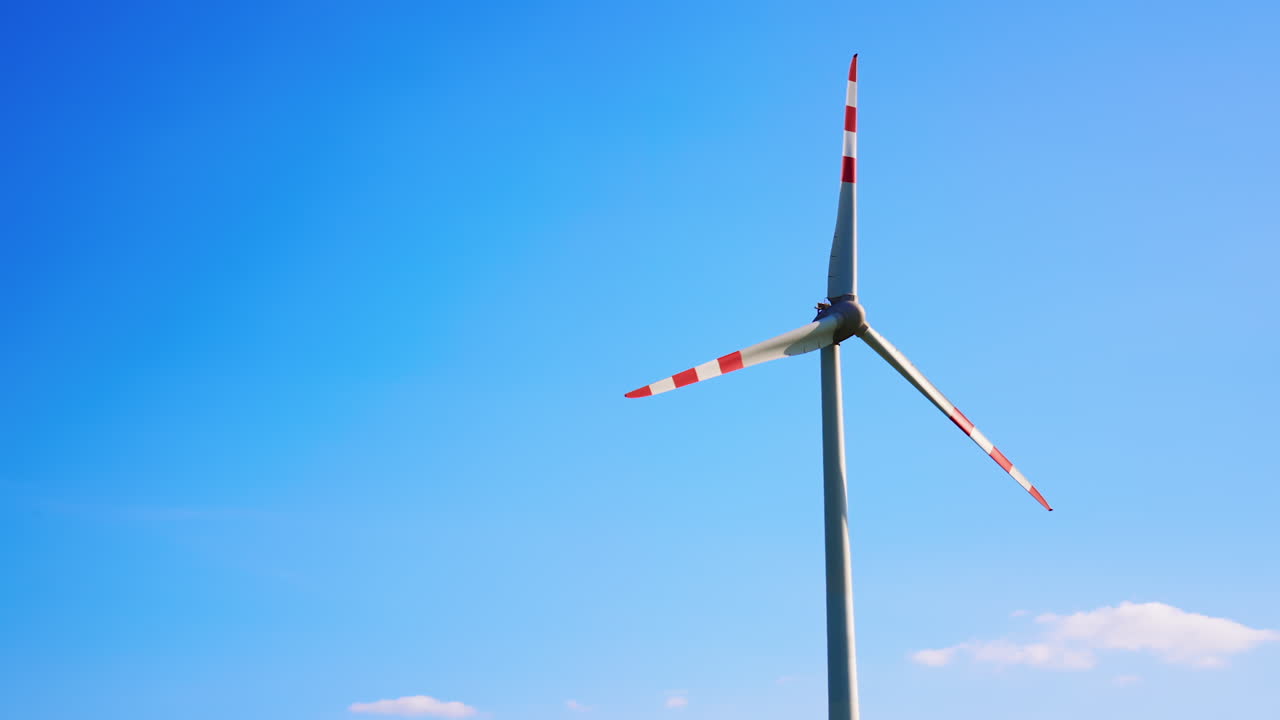 Wind turbine against bright blue sky. A tall wind turbine stands prominently, with colorful blades spinning under a clear blue sky during daytime