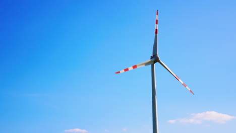 wind turbine against bright blue sky. a tall wind turbine stands prominently, with colorful blades spinning under a clear blue sky during daytime