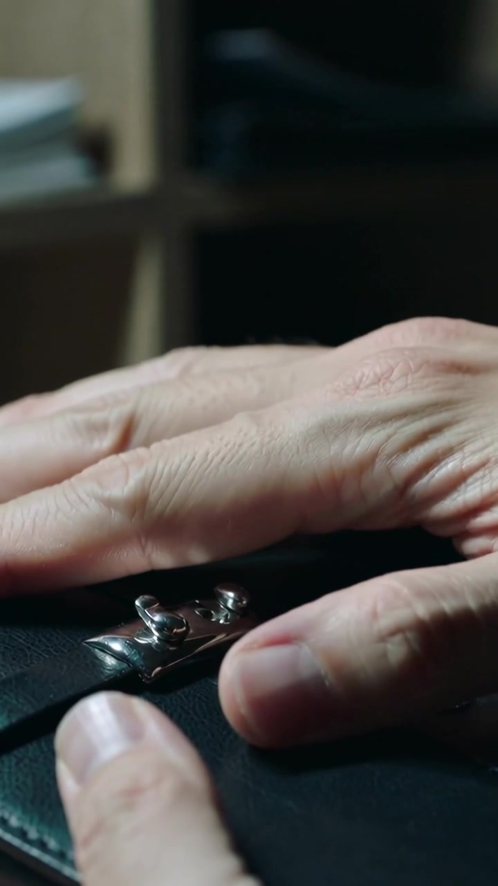 Vertical video: Entering right hand grazing black pouch, manipulating silver clasp to open at desk
