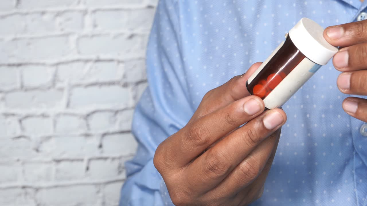 persona que sostiene un frasco de pastillas