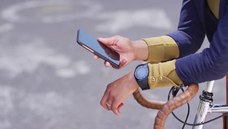 african american woman using smartphone in street leaning on bicycle