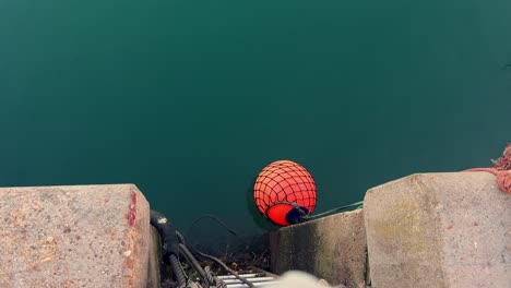 A-vibrant-red-buoy-is-secured-to-a-water-dock,-epitomizing-the-maritime-ambiance-of-a-quaint-fishing-village