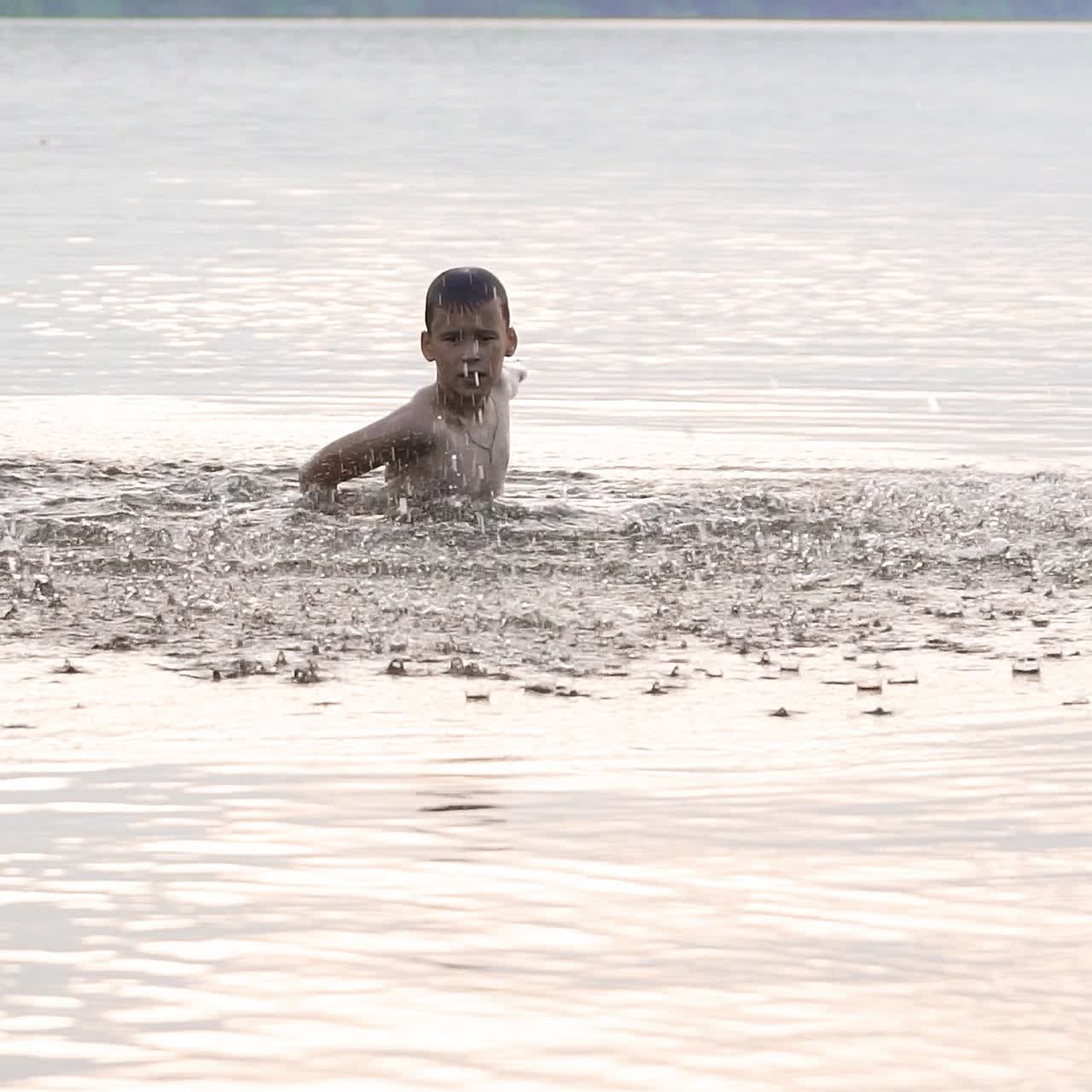 Slow motion of happy little child having enjoyable time in the river. He laughing and splashing water