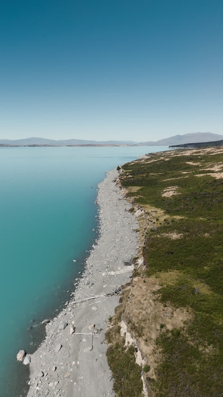 Aerial View of Turquoise Lake with Rocky Shoreline and Mountains