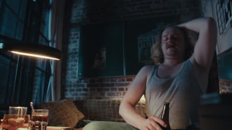 man drinking and smoking in his apartment at night