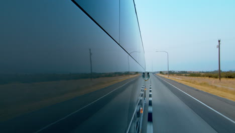 side view of a public bus, shuttle, or school bus driving and the road reflection on it