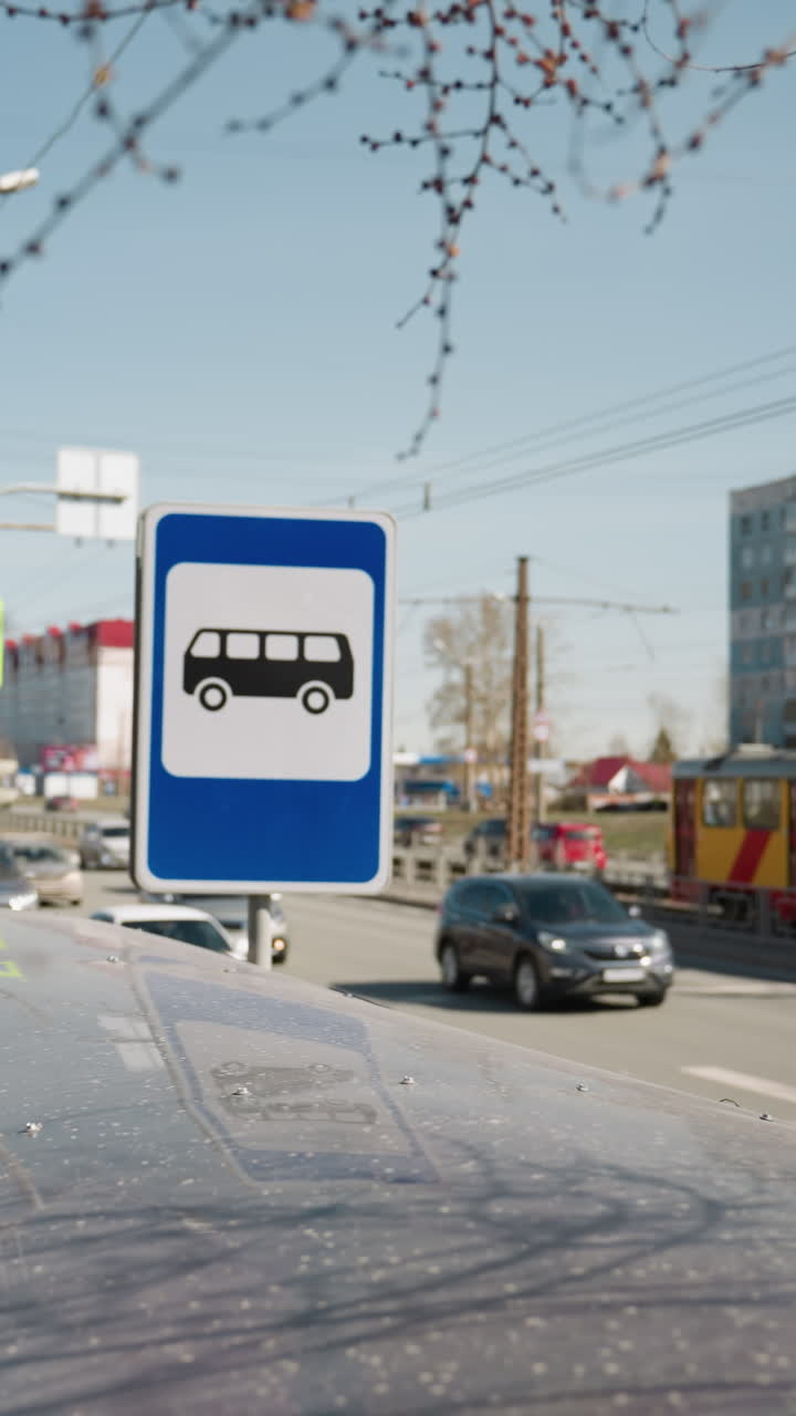 vista de la ciudad con un letrero de parada de autobús, tráfico y un tranvía en un día soleado, con coches pasando, con cielos azules claros y una atmósfera animada