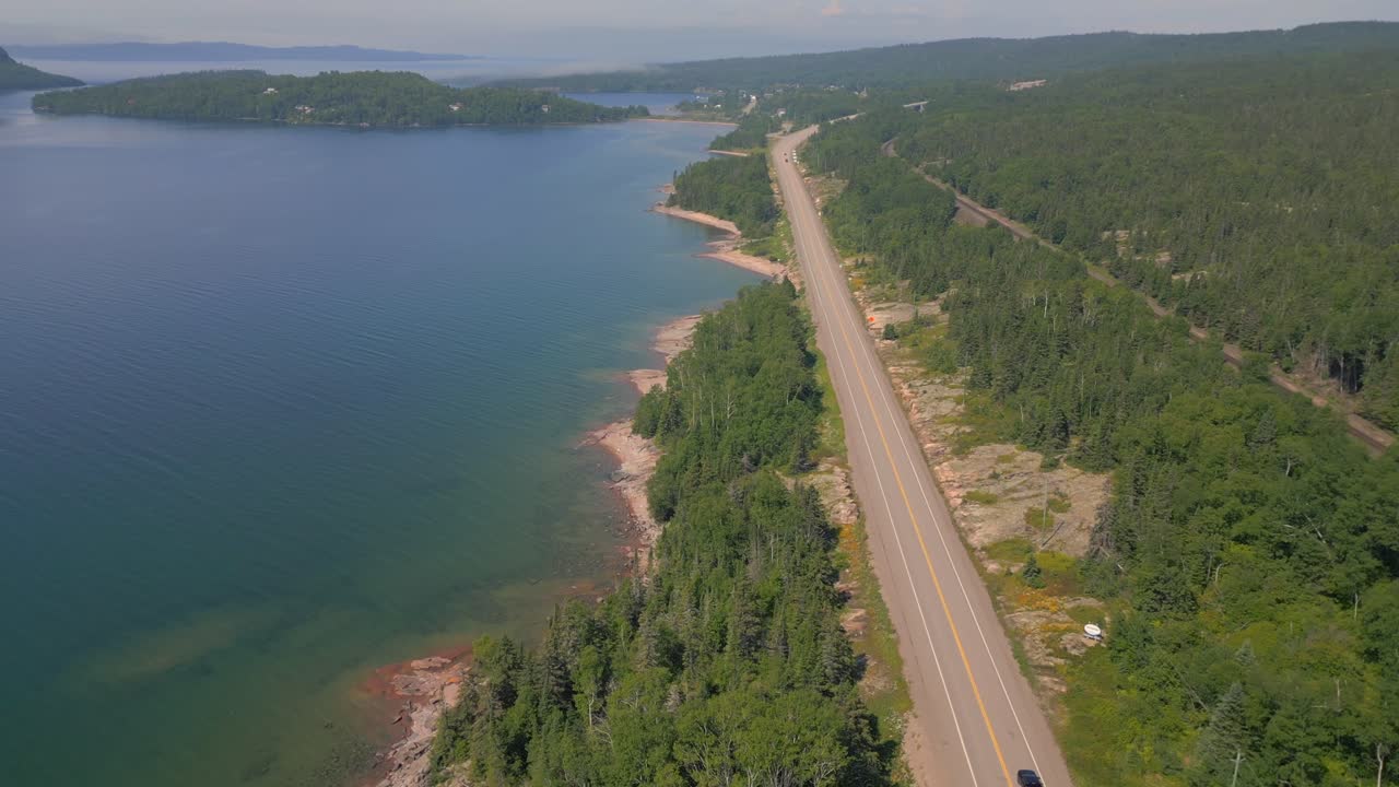 Aerial view of a road along a lake and forest