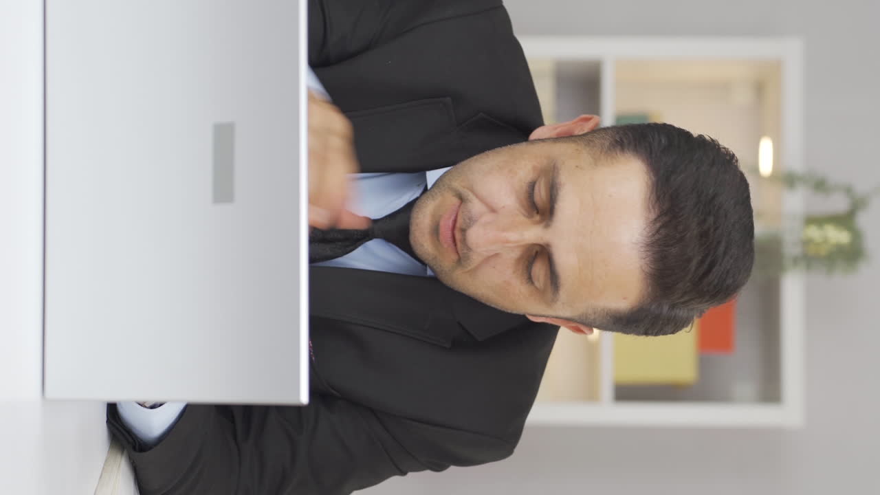 vídeo vertical de un hombre que trabaja en una oficina en casa teniendo un ataque al corazón.